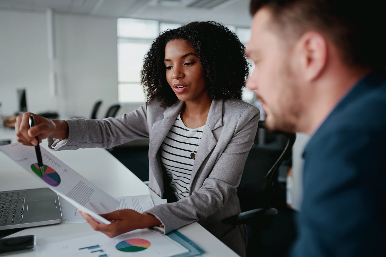Two businesspeople looking at a financial report and having a discussion in office